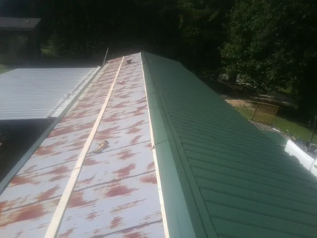 Old rusted panels beside newly installed green metal roofing — Wind Damage Roof Repair by Roofing Brothers in Gazelle