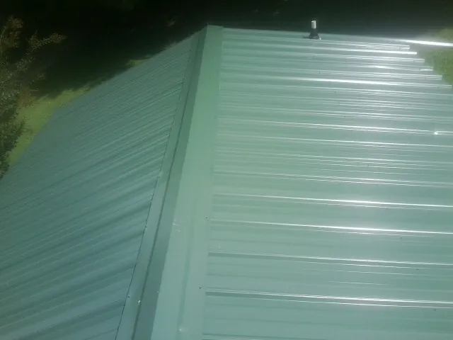 New green metal panels meeting at the ridge of a roof — Flat Roof Repair work by our crew in Gazelle