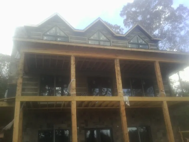 Dormers and porch framing on a large log home under construction — Roof Coating work by our crew in Gazelle