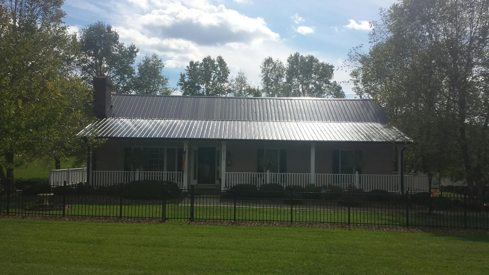 Gray metal roof on a brick ranch with a full width front porch — Gutter Guard Installation work by our crew in Gazelle