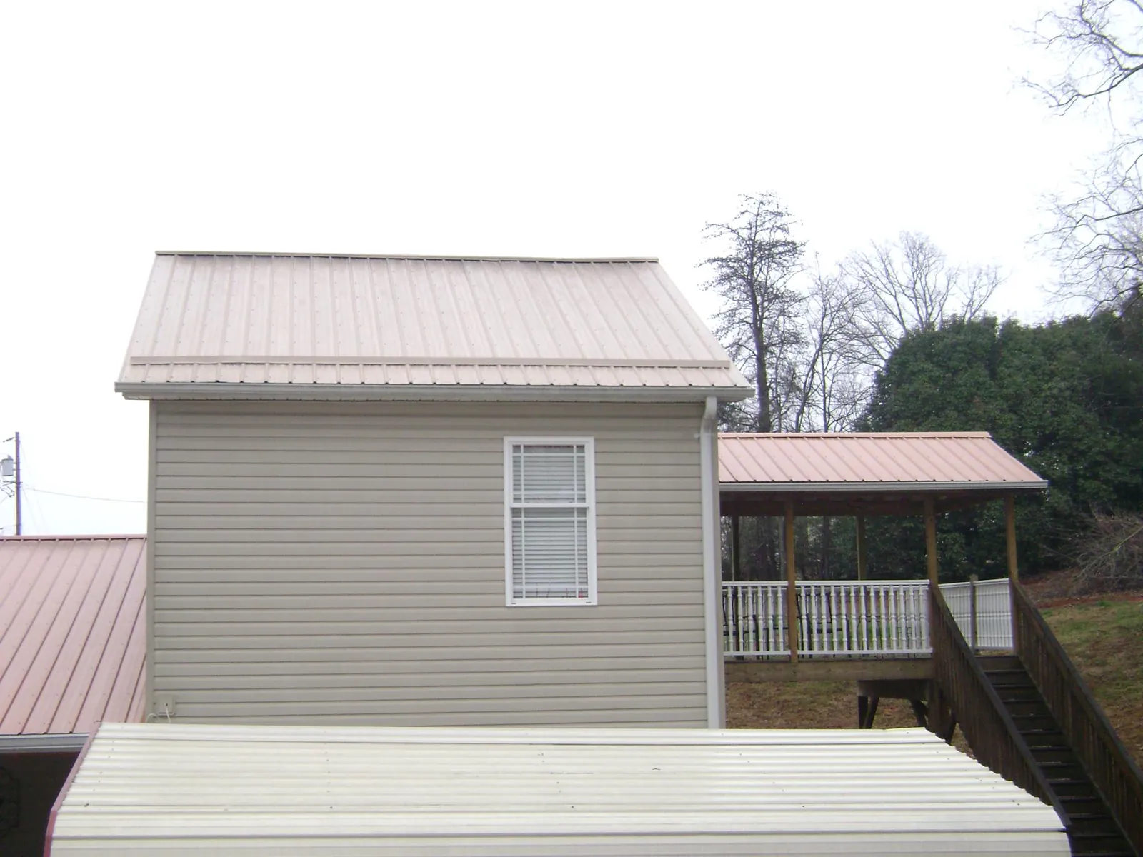 Tan metal roofs on a two story addition and attached porch, from a Roof Replacement job in Gazelle