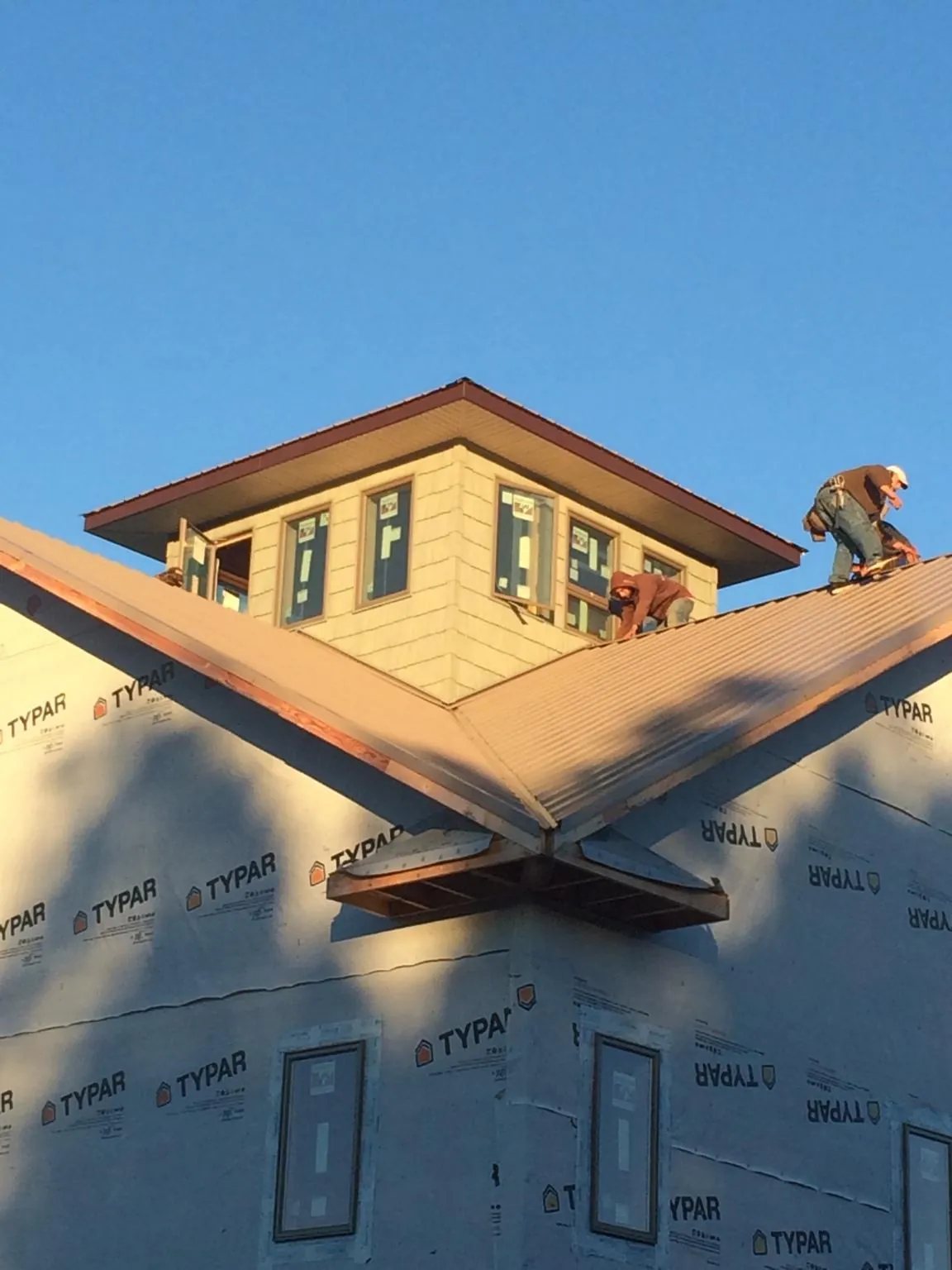 Roofers working around a rooftop cupola on a new metal roof at sunset — Roof Waterproofing in Gazelle by Roofing Brothers